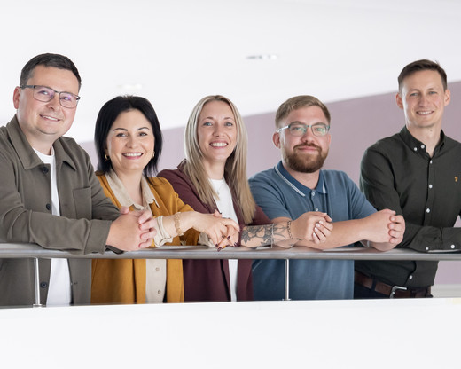 Gruppenfoto: Frauen und Männer lehnen am Geländer
